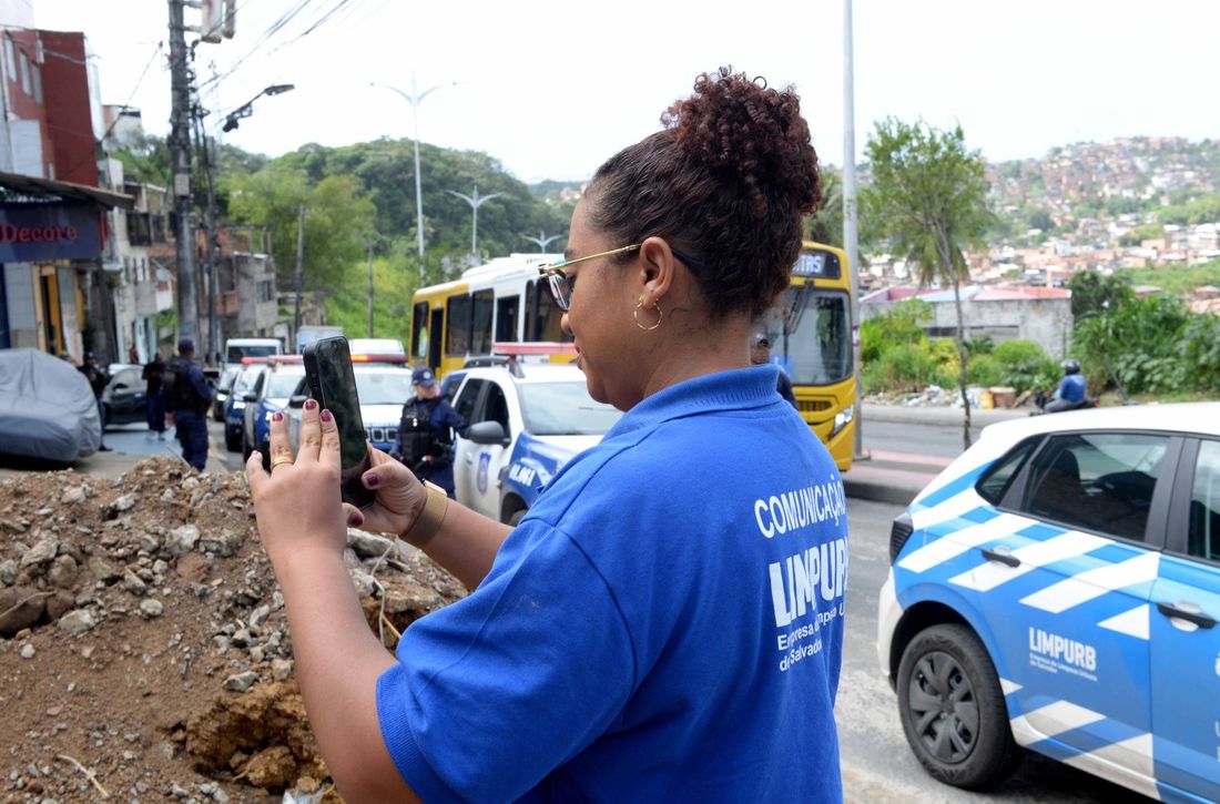 Priscila gravando com o celular nas ruas de Salvador, de uniforme da Limpurb